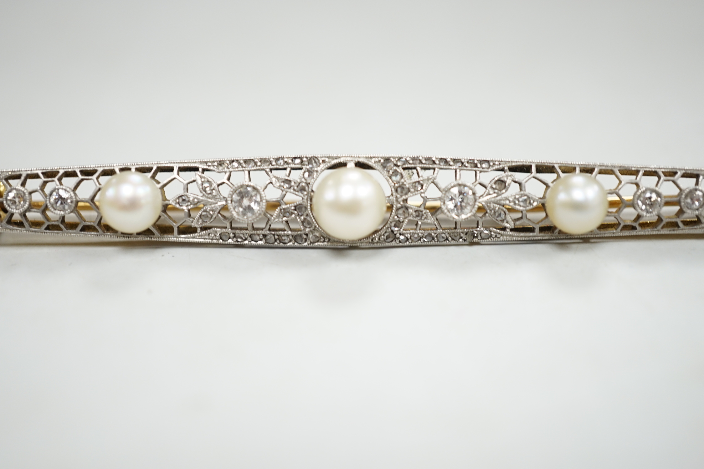 A Belle Epoque pierced yellow and white metal, cultured? pearl and diamond set bar brooch, 84mm, gross weight 10 grams, in fitted leather box.